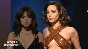 Aubrey Plaza in a brown sequined dress with a cutout, standing next to a woman in a black dress behind a microphone.