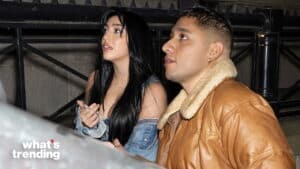 Two people sitting and looking upward, one wearing a brown shearling jacket and the other a denim jacket.