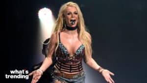 Britney Spears performing on stage wearing a bejeweled top and denim shorts with a headset microphone