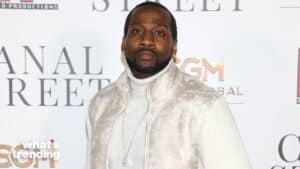 Man wearing a white turtleneck and textured jacket at a Canal Street event backdrop