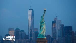Statue of Liberty with One World Trade Center and New York City skyline at dusk