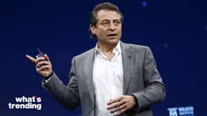 Peter Diamandis speaking at the Milken Institute event, wearing a gray checked blazer and white shirt.