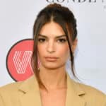 Emily Ratajkowski wearing a beige blazer with hair up at a Conde Nast event backdrop