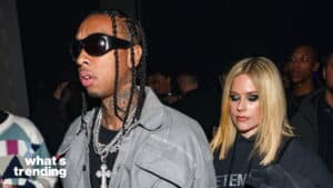 Tyga wearing sunglasses and chains with Avril Lavigne in a black hoodie at a crowded event