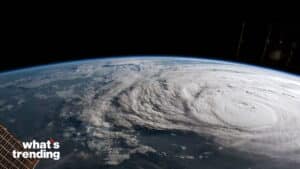 Satellite view of a large hurricane swirling over Earth with part of a space station visible