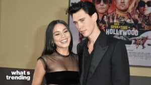 Vanessa Hudgens and Austin Butler posing at a red carpet event with a "Once Upon a Time in Hollywood" poster in the background