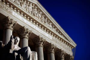 Statue of a seated figure in front of the U.S. Supreme Court building with "Equal Justice Under Law" inscription