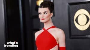 Woman in a red halter dress with braided updo and bold makeup at a formal event with CBS logo background
