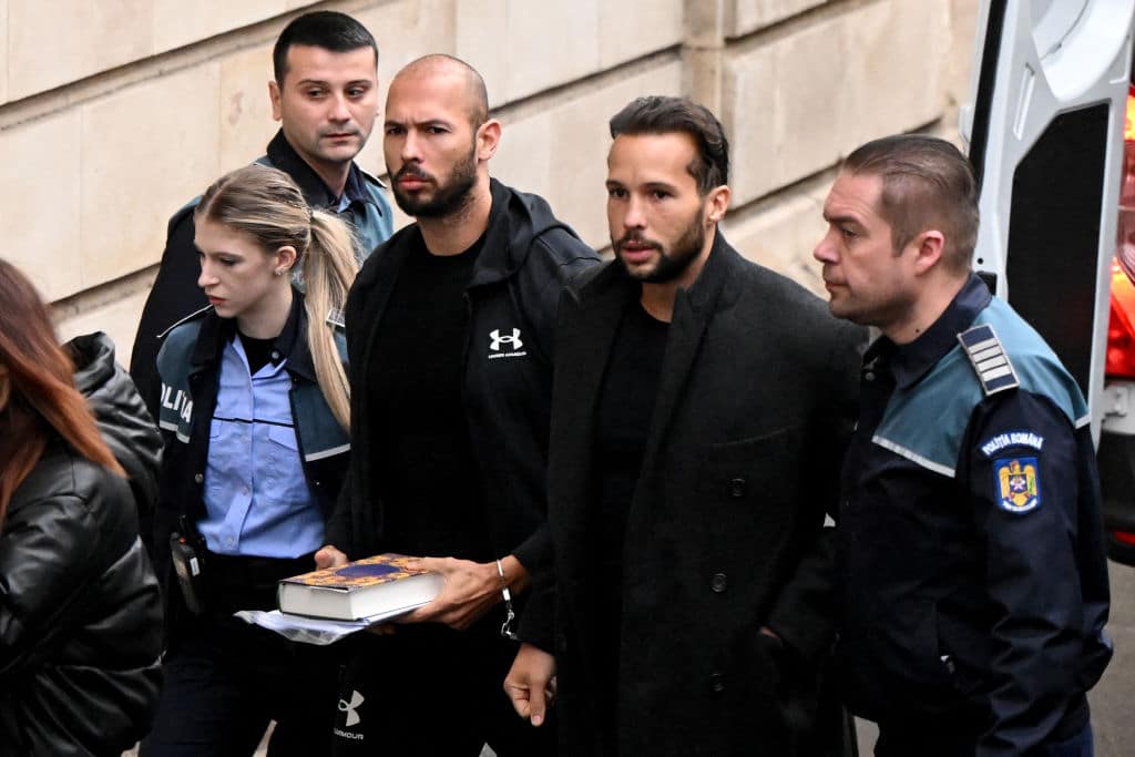 British-US former professional kickboxer and controversial influencer Andrew Tate (3rd R) and his brother Tristan Tate (2nd R) arrive handcuffed and escorted by police at a courthouse in Bucharest on January 10, 2023 for a court hearing on their appeal against pre-trial detention for alleged human trafficking, rape and forming a criminal group. 
