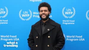 The Weeknd smiling in a black coat and tie at the UN World Food Programme event backdrop