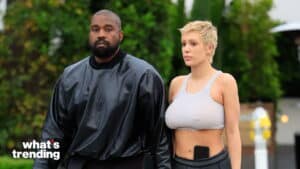 Kanye West and Julia Fox walking outdoors, Kanye in a black jacket and Julia in a gray crop top with a phone in her waistband
