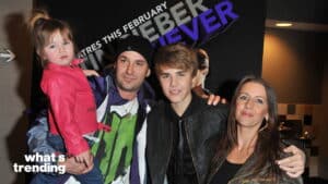 Justin Bieber posing with a man holding a child and a woman at a promotional event for "Justin Bieber: Never Say Never"