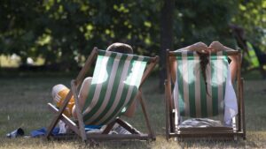 LONDON, ENGLAND - JULY 18: A couple relax on deckchairs in the warm weather in Hyde Park on July 18, 2014 in London, England. The Met Office has issued a heatwave alert as temperatures soar to their highest of the year.