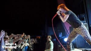 Female singer with red hair performing on stage in leopard print pants with an enthusiastic audience reaching out