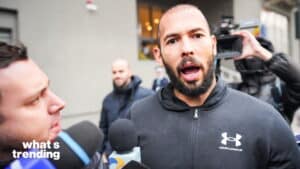 Man in Under Armour jacket speaking to reporters with microphones and camera outdoors