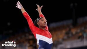 Simone Biles performing a gymnastics routine wearing a red, white, and blue USA leotard.
