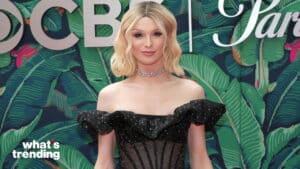 Person with blonde hair wearing a black off-shoulder dress and choker necklace against a green leafy CBS backdrop