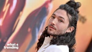 Ezra Miller with long curly hair styled in braids and a white outfit at a red carpet event