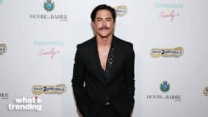 Man in black suit with patterned shirt posing at event with House of Barrie and Back 2 Originals logos on backdrop