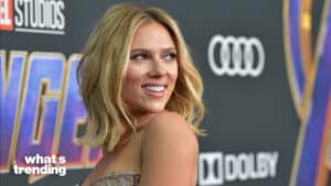 Scarlett Johansson smiling on the red carpet at a Marvel Avengers event with Marvel Studios and Audi logos visible