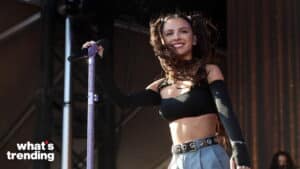 Olivia Rodrigo performing on stage with a purple microphone stand and black crop top.