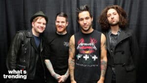 Four men posing in front of a black curtain, one wearing a Metallica Master of Puppets sleeveless shirt.