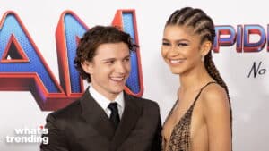 Tom Holland and Zendaya smiling at the Spider-Man No Way Home premiere event.