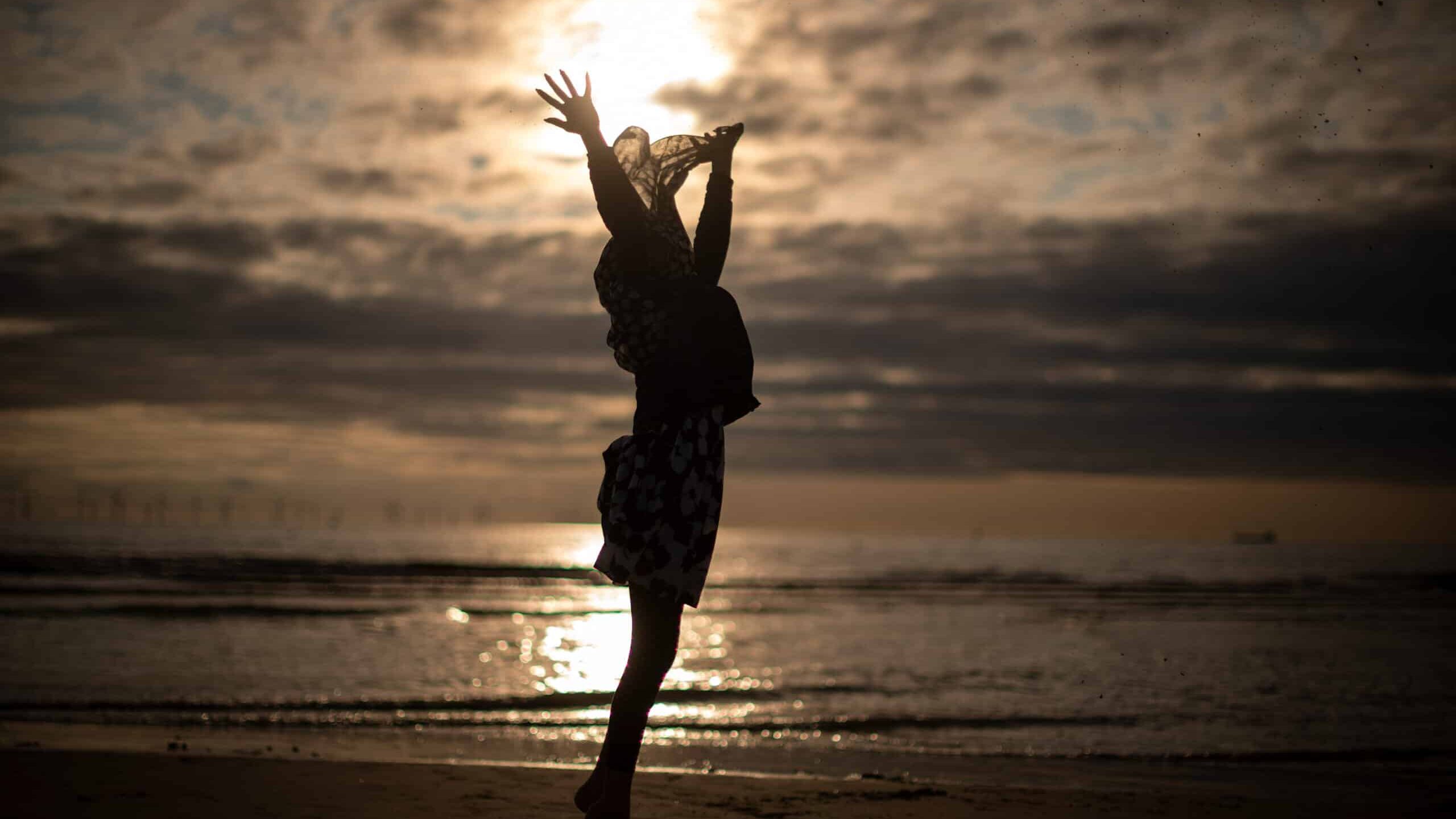 LIVERPOOL, UNITED KINGDOM - AUGUST 21: A young muslim girl dances and runs in the sea as she and her family celebrate Eid Al-Adha by watching the sunset at Crosby beach on August 21, 2018 in Liverpool, England. The traditional four-day celebratory festival marks one of the holiest days in the Islamic religious calendar.