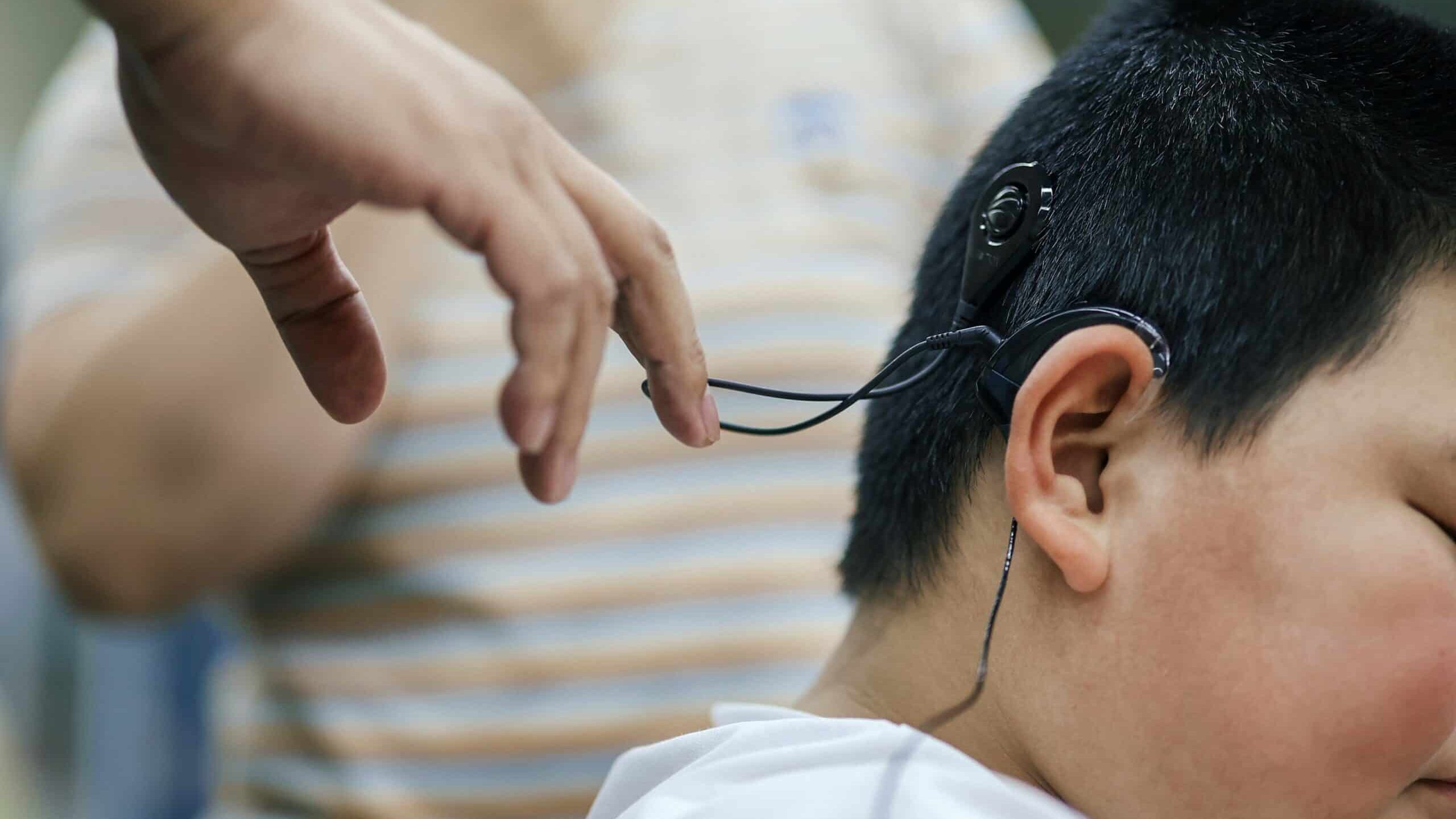A staff member helps a child start up his cochlear implant for the first time in Changchun, northeast China's Jilin Province, May 15, 2023. In recent years, Jilin Province has continued to improve the policy of rehabilitation and treatment for hearing-impaired children, and has provided free cochlear implant operations for more than 1,000 children.