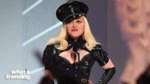 Madonna wearing a black leather outfit and hat speaking at a microphone on stage