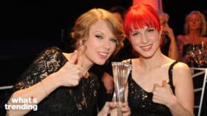 Taylor Swift and Hayley Williams smiling and giving thumbs up while holding a trophy at an event