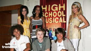 Cast members of High School Musical posing in front of a promotional poster