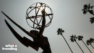 Emmy Award statue silhouette with sun shining through the globe and palm trees in the background