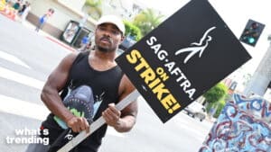 Man holding a "SAG-AFTRA ON STRIKE!" sign during a street protest