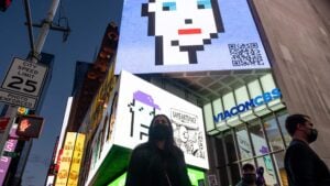 NEW YORK, NEW YORK - MAY 12: People walk past CryptoPunk digital art non-fungible token (NFT) displayed on a digital billboard in Times Square on May 12, 2021 in New York City. The image is part of SaveArtSpace's "Pixelated" public art exhibition which will be displaying 193 of Larva Labs' CryptoPunks on phone booths, bus shelters, and billboards around New York City during the month of May. New York Governor Andrew Cuomo announced pandemic restrictions to be lifted on May 19.