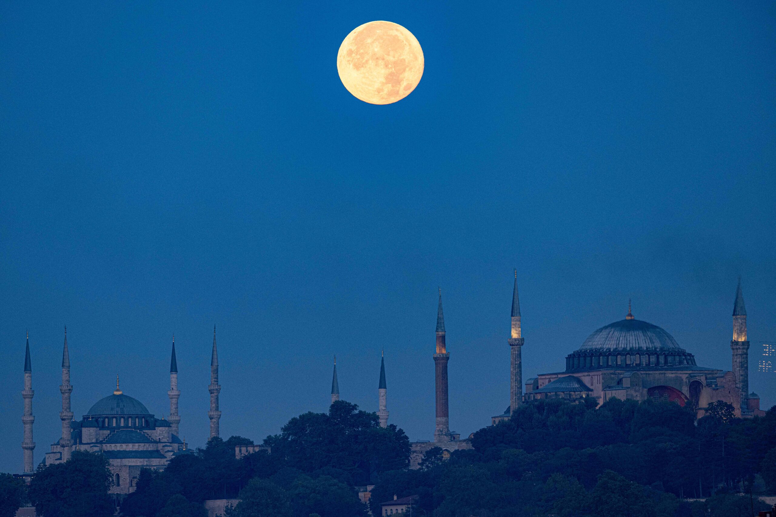 The Sturgeon super moon rises over the Blue Mosque and Ayasofya-i Kebir Camii or Hagia Sophia Grand Mosque in Istanbul on August 2, 2023. 