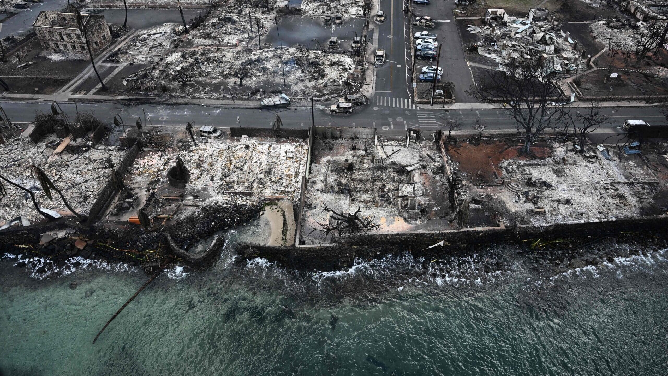 An aerial image taken on August 10, 2023 shows destroyed homes and buildings burned to the ground in Lahaina along the Pacific Ocean in the aftermath of wildfires in western Maui, Hawaii. A terrifying wildfire that left a historic Hawaiian town in charred ruins has killed at least 55 people, authorities said on August 10, making it one of the deadliest disasters in the US state's history. (Photo by Patrick T. Fallon / AFP)
