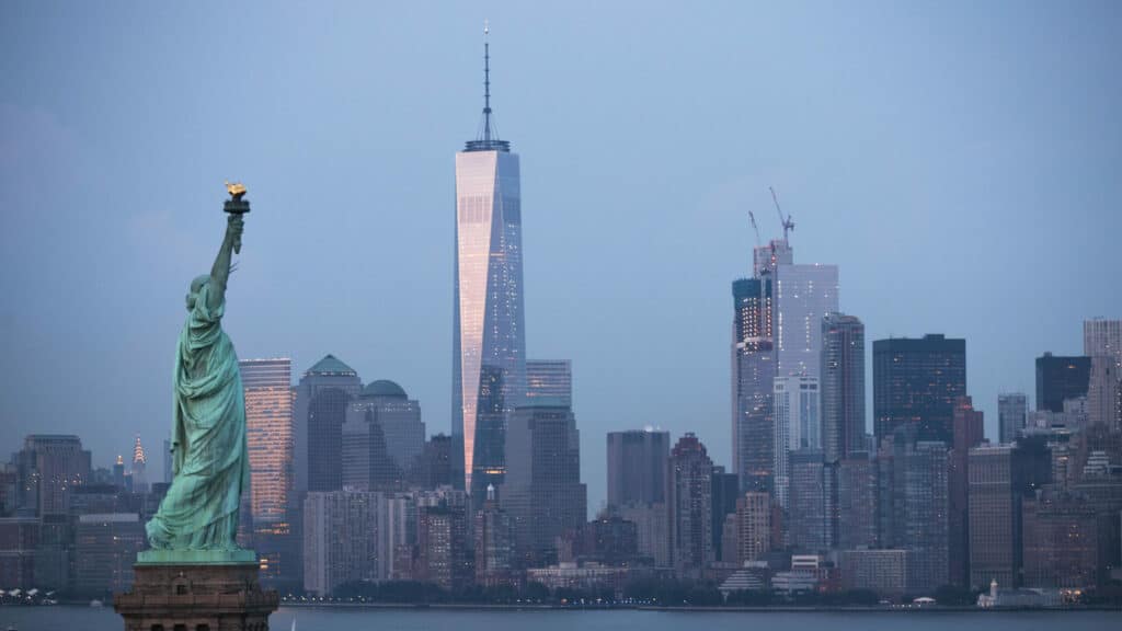 The Statue of Liberty stands in the foreground as Lower Manhattan is viewed at dusk.