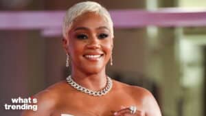 Tiffany Haddish smiling with short blonde hair, wearing a silver chain necklace and earrings