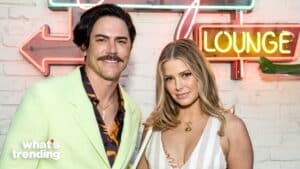 Man in light green blazer and woman in striped dress posing in front of neon "Lounge" sign