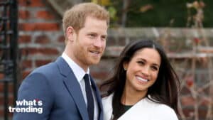 Prince Harry and Meghan Markle smiling outdoors near a brick wall