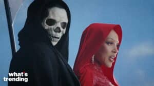 Person in a black hood and skull mask standing next to a woman in a red hooded outfit against a blue sky background