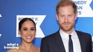 Meghan Markle and Prince Harry smiling at a Robert F. Kennedy Human Rights event with a blue background.