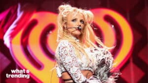 Britney Spears performing on stage with a headset microphone and a white lace outfit with feather details