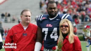 Ole Miss football player in jersey 74 with two adults holding flowers on a stadium field.