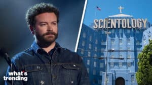 Danny Masterson with a serious expression next to the Church of Scientology building with a large sign and cross.