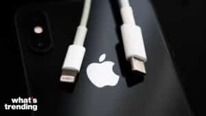 Apple logo on a black iPhone with a Lightning cable and a USB-C cable placed above it.