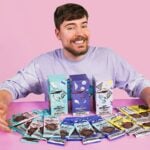 MrBeast poses in front of the different kinds of chocolate bars Feastables offers.