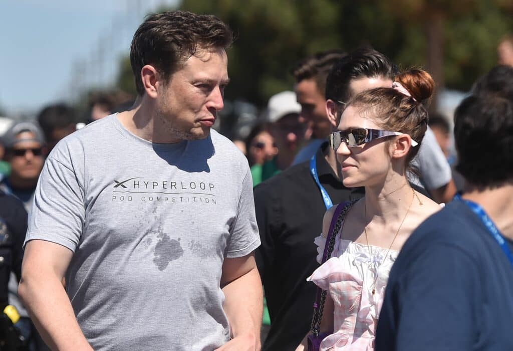 SpaxeX founder Elon Musk (L) and Canadian musician Grimes (Claire Boucher) attend the 2018 Space X Hyperloop Pod Competition, in Hawthorne, California on July 22, 2018. - Students from colleges and universities from the US and around the world are taking part in testing their pods on a 1.25 kilometer-long (0.75-mile) tubular test track at the SpaceX headquarters.