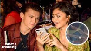 Tom Holland and Zendaya looking at a phone together at an event, Zendaya wearing a green embellished dress.